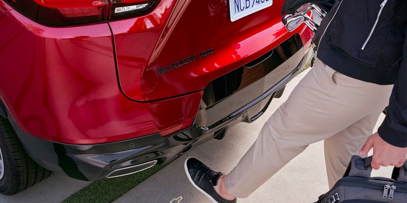 person waving foot under the rear bumper of a 2024 chevy blazer to open hatchback hands free