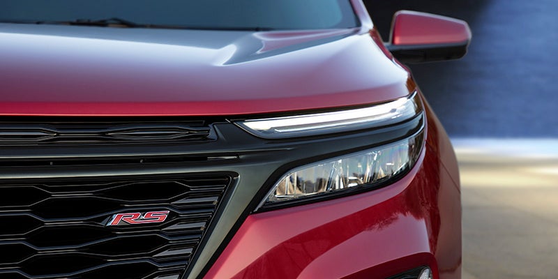 close up of front grille and headlight of a red 2024 chevy equinox displaying the RS trim emblem