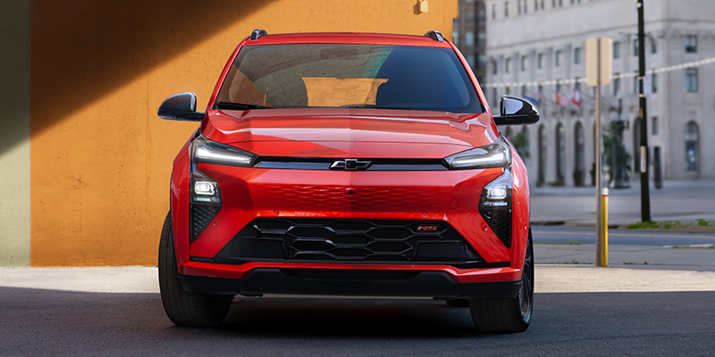 Red Chevrolet Bolt parked in front of a colorful orange wall
