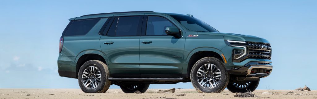 Dark green Chevrolet Tahoe SUV parked on a sandy field.