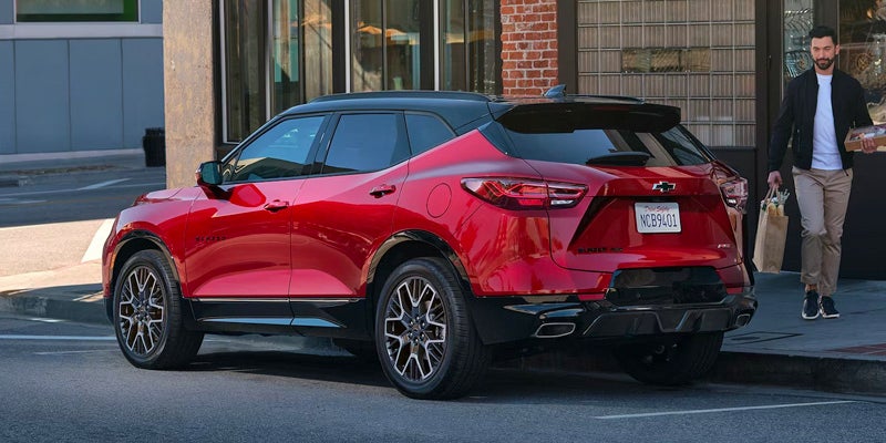 left rear view of a red 2024 chevy blazer parked outside a store front