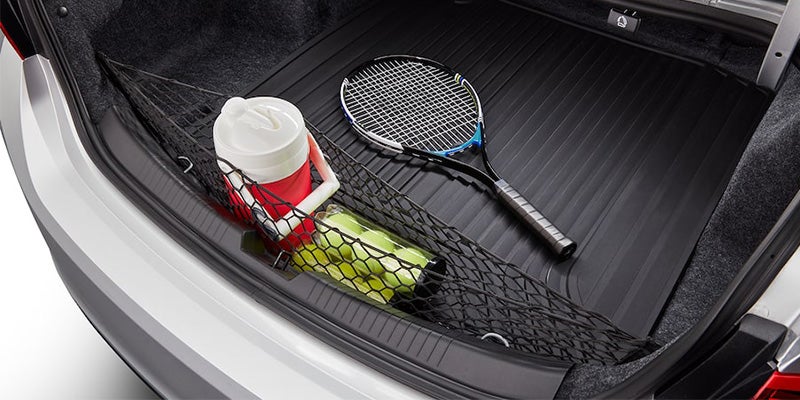 2024 chevy malibu cargo space in truck with netting holding tennis balls, a small cooler and a racket