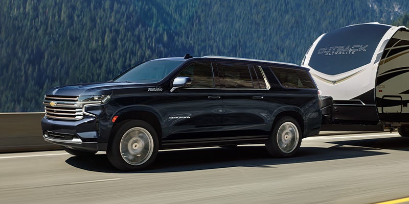 navy blue 2024 chevy suburban towing an RV